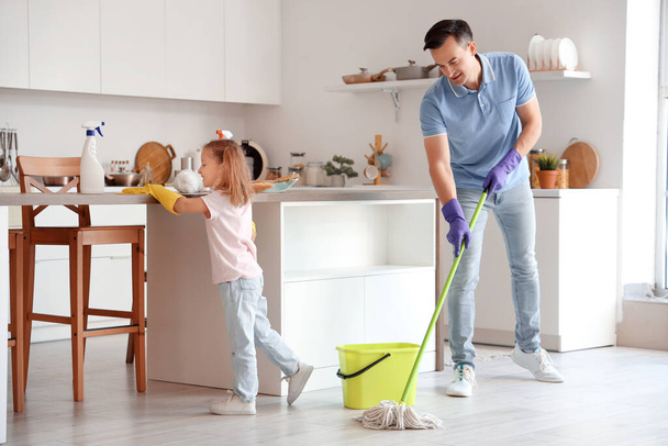 Cute little girl with her dad cleaning in kitchen - Photo, Image
