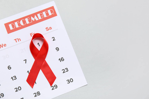 Red ribbon with calendar for December on light background, closeup. AIDS Day concept - Photo, Image