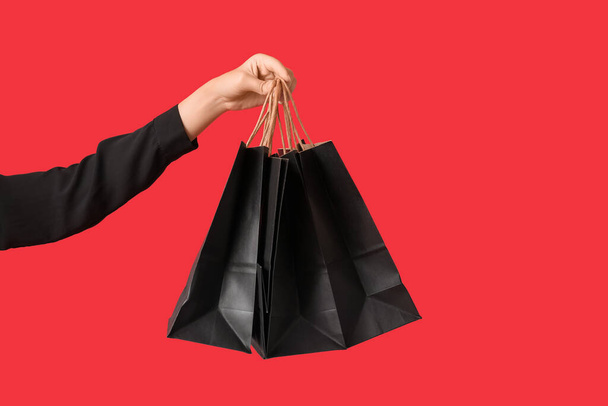 赤い背景のショッピングバッグ付き女性手. ブラックフライデーセール - 写真・画像
