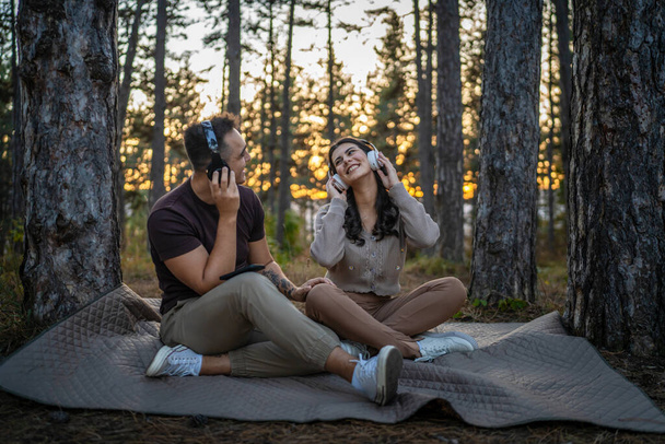 Erkek ve kadın, genç yetişkin bir çift kulaklıkla müzik dinliyor. - Fotoğraf, Görsel