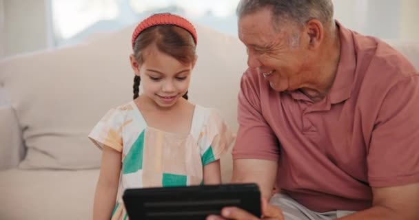 Happy, tablet and grandfather with child on sofa networking on social media in living room of home. Smile, love and senior man in retirement bond, relax and scroll on digital technology with girl kid. - Footage, Video