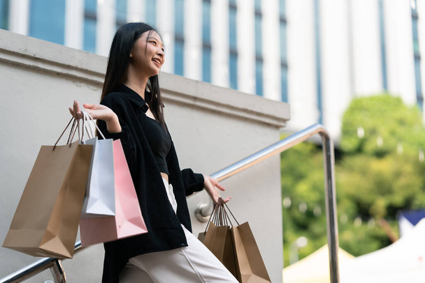 Young asian woman in shopping. Fashion woman in black with shopping bag walking out store after shopping. Black friday. - Photo, Image