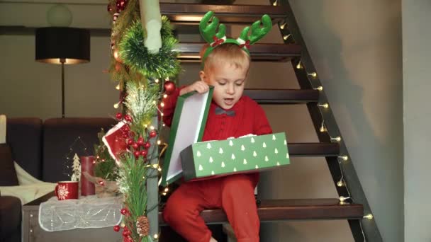 Upset and angry toddler boy opens his Christmas gift and gets disappointed throwing down the present box from Santa - Footage, Video