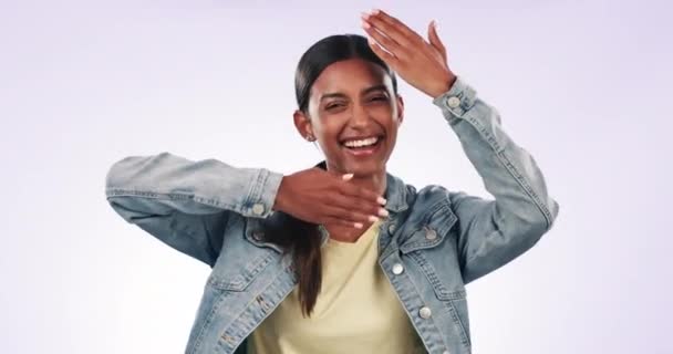 Hands, comic and the funny face of an indian woman in studio on a gray background for emoji expression. Portrait, smile and emotion with a happy young model in trendy clothes for fashion or style. - Footage, Video