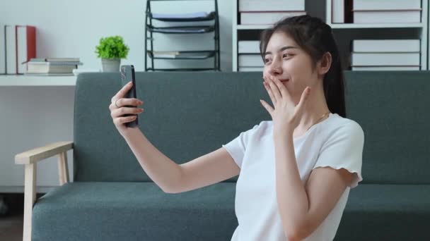 Mujer asiática guapa usando su teléfono tomando una selfie en una pose dulce beso mientras está de vacaciones en casa. Imágenes de alta calidad 4k - Imágenes, Vídeo