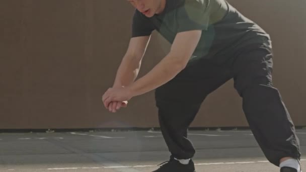 Νεαρός αθλητικός Καυκάσιος τύπος κάνει πλευρική lunge άσκηση κατά τη διάρκεια της υπαίθριας προπόνηση το ηλιόλουστο πρωί - Πλάνα, βίντεο