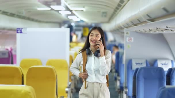 アジア系の可愛い10代の女の子が友人と電話で話している間、彼女の毎年の休暇、旅行者の概念のための飛行機に乗っている。高品質4k映像 - 映像、動画