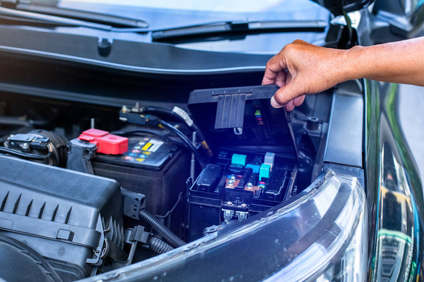 Een monteur opent de afdekking van een auto 's elektrische systeem controledoos. Autozekeringkast. - Foto, afbeelding