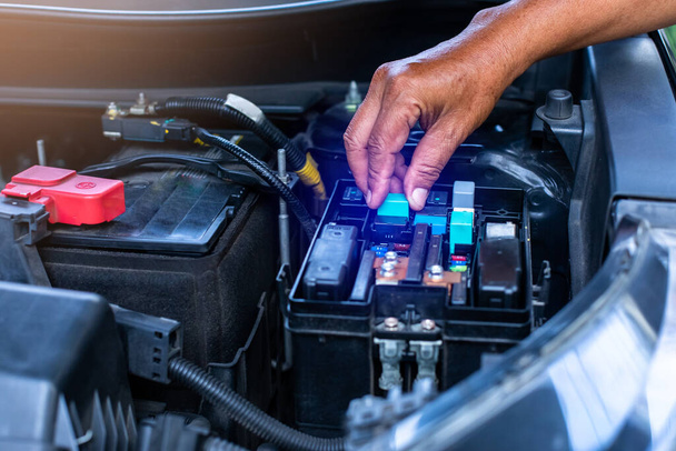 Ein Mechaniker öffnet die Abdeckung des elektrischen Schaltkastens eines Autos. Sicherungskasten für Auto. - Foto, Bild