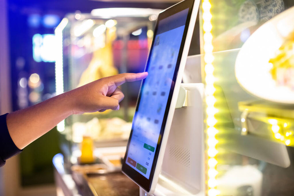 Селективным фокусом на руку клиента является прикосновение к сенсорному экрану, чтобы заказать еду и заплатить в электронном виде. Цифровой заказ. - Фото, изображение