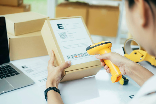 Çevrimiçi kadın satıcı elinde tarayıcı taraması barkod etiketi paketleme ekommerce posta kutusu indirme teslimat deposunda çevrimiçi perakende mağaza siparişlerini kontrol etme. - Fotoğraf, Görsel