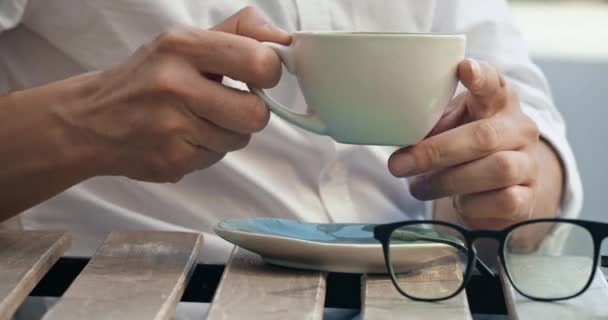 Freelancer agarra taza de café durante el trabajo a distancia al aire libre. Empresario trabajador remoto se sienta a la mesa bebiendo taza de café caliente después del trabajo - Imágenes, Vídeo