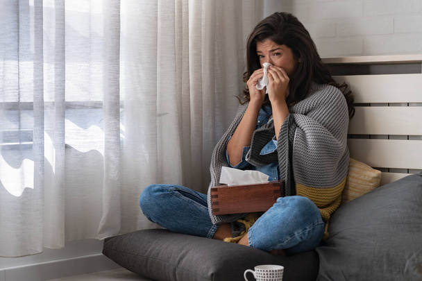 Mladá žena doma si utírá nos, kýchá, má rýmu, chřipku, alergii. Snažím se zahřát. - Fotografie, Obrázek