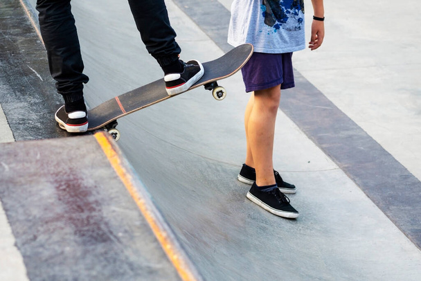The skateboarder before descent from the hill. The guy shows to the friend how to go down on a board. Concept of Healthy lifestyle. Sports hobby.The guy on a skateboard.  Sports hobby. Skateboard active urban life style.  man in a sports helmet on th - Foto, afbeelding