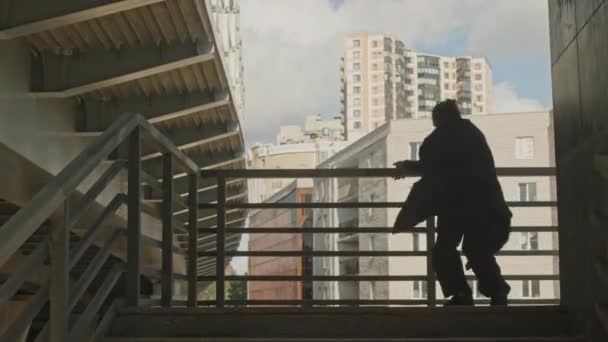 Aktywny młody kaukaski facet robi akrobatyczne parkour akrobacje na zewnątrz schody na terenie przemysłowym - Materiał filmowy, wideo