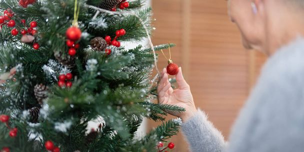 Neşeli yaşlı kadın Noel ağacını süslüyor. Noel atmosferi rahat ev içinde. - Fotoğraf, Görsel