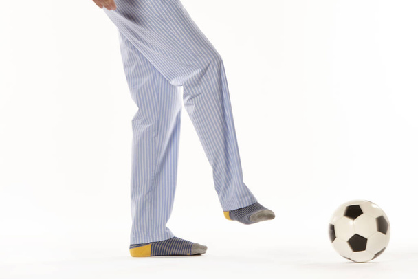 Egy fiatalember pizsamában focizik. Lábak. Éjszakai viselet - Fotó, kép