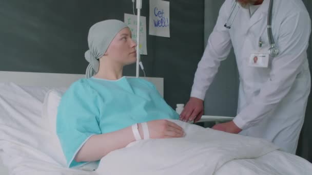 Médecin mature en manteau blanc préparant compte-gouttes médicaux pour la chimiothérapie pour les jeunes patientes atteintes de cancer en salle d'hôpital - Séquence, vidéo