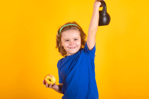 Słodki chłopiec pompuje mięśnie ramion za pomocą dzwonka. Dzieci fitness z hantlami - Zdjęcie, obraz
