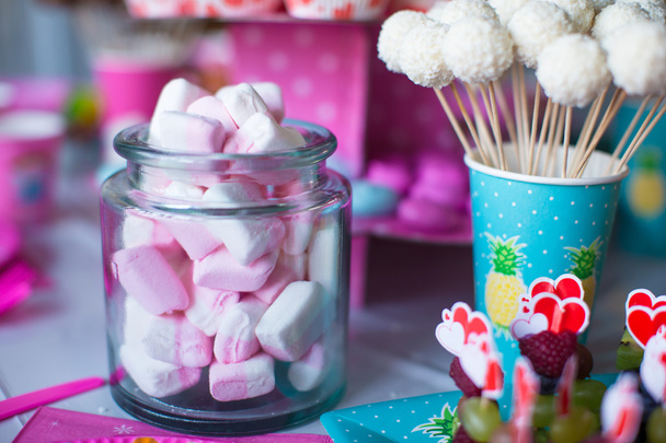 Marshmallow, merengues de cor doce, pipocas, bolos de creme e bolos pops na mesa
 - Foto, Imagem