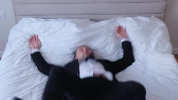 Tired young businessman in suit lying on bed in hotel, just arrived. Business trip. - Footage, Video