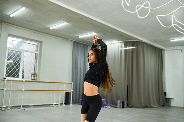 expresivní afroamerická tanečnice v černém oděvu nacvičující v tanečním studiu, rytmický pohyb - Fotografie, Obrázek