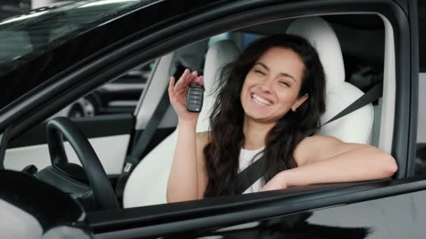 Lachende mooie dame die de sleutel van een nieuwe auto laat zien terwijl ze op de bestuurdersstoel zit. Rijtest, transportconcept. Langzame beweging - Video