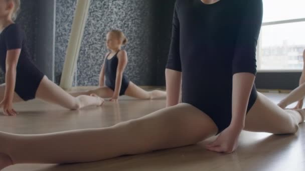 Schnappschuss einer Gruppe von Mädchen, die auf dem Boden des Tanzstudios sitzen und Split üben - Filmmaterial, Video