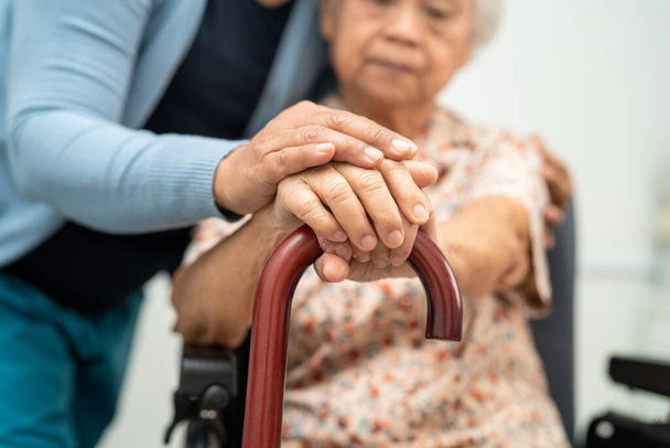 Φροντιστής βοηθήσει Ασιάτισσα ηλικιωμένη γυναίκα ασθενή με αγάπη, φροντίδα, ενθάρρυνση και ενσυναίσθηση στο νοσηλευτικό νοσοκομείο, υγιή ισχυρή ιατρική έννοια. - Φωτογραφία, εικόνα