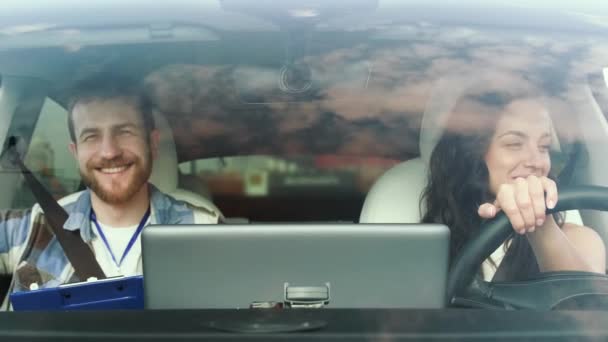 Jovem sorridente e instrutor masculino usando cinto de segurança enquanto sentado no carro durante o teste de condução. Teste de condução, conceito de transporte. Movimento lento - Filmagem, Vídeo