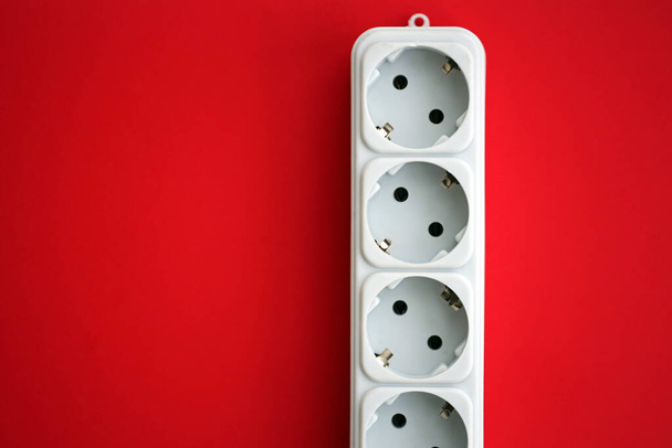 Λευκό ηλεκτρικό multi plug extender με ευρωπαϊκή υποδοχή σε έντονο κόκκινο φόντο close up - Φωτογραφία, εικόνα