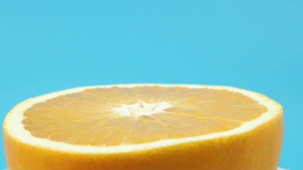 Rijpe sinaasappels draaien op een blauwe achtergrond. Oranje close-up op blauw. - Video