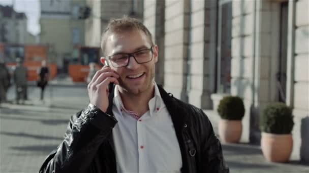 Handsome young man walking and talking on the phone, slow motion. - Materiał filmowy, wideo