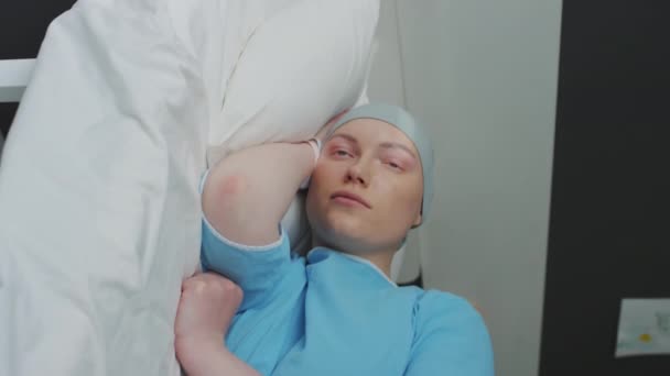 Senkrechte Aufnahme einer krebskranken depressiven Frau, die im Krankenhaus mit Kopftuch auf dem Bett liegt und direkt vor sich hinstarrt - Filmmaterial, Video