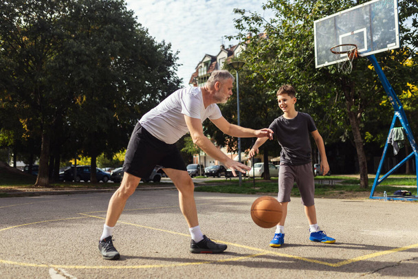 Dojrzały mężczyzna gra w koszykówkę ze swoim synem - Zdjęcie, obraz
