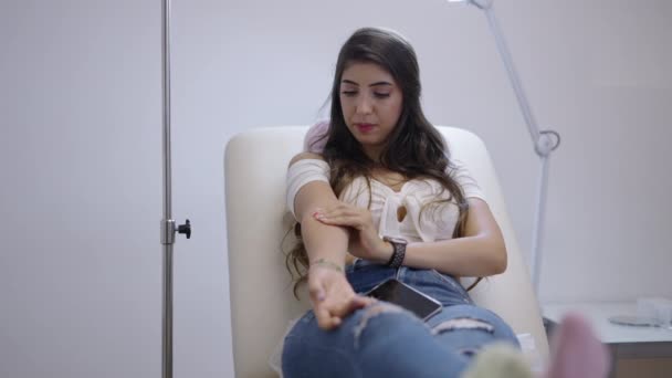 Gyönyörű spanyol beteg integetett a kamerába, miközben préselte a pamut gyapjú a karján - 4K Horizontális videó - Felvétel, videó