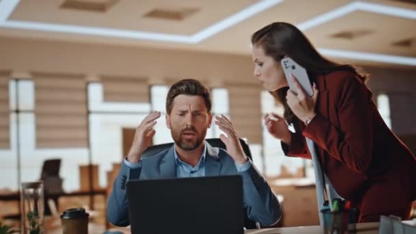 Stressed business couple working at big cabinet. Frustrated director closed face with hands at laptop workplace interior. Woman partner solving problems on smartphone call feeling nervous at office  - Footage, Video