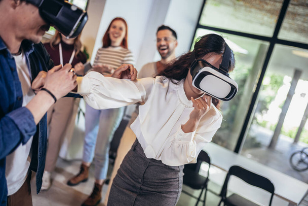Empresários que fazem exercício de treinamento em equipe durante o seminário de formação em equipe usando óculos VR
 - Foto, Imagem