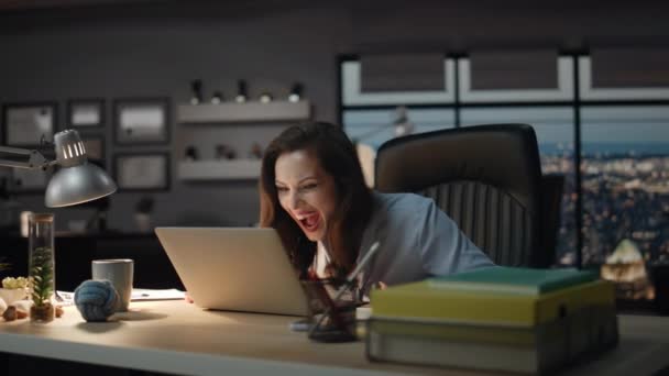Vrouwelijke winnaar op zoek laptop vieren succes in avondkantoor. Gelukkige baas schreeuwend luid genietend van zakelijke prestaties. Emotionele dame gebaren handen spannend door goed nieuws in donkere kast  - Video