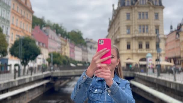 Una turista donna scatta foto di una bella città europea sul suo smartphone. - Filmati, video