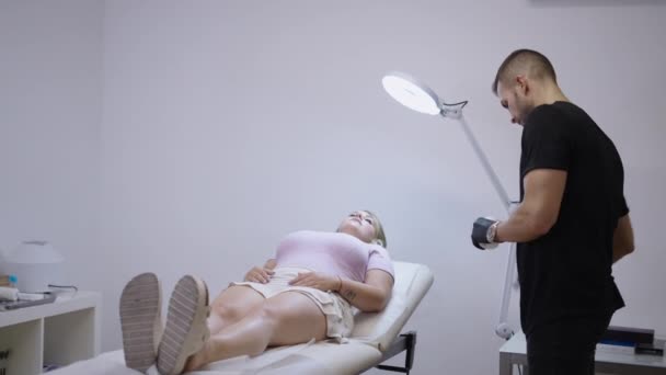 Блондинка лежить, отримуючи знеболюючий крем від лікаря - концепція охорони здоров'я - Кадри, відео