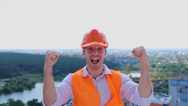 Succès homme travailleur de la construction en casque dur célébrant la victoire sur le chantier de construction. Entreprise, bâtiment, concept industriel. Temps réel - Séquence, vidéo