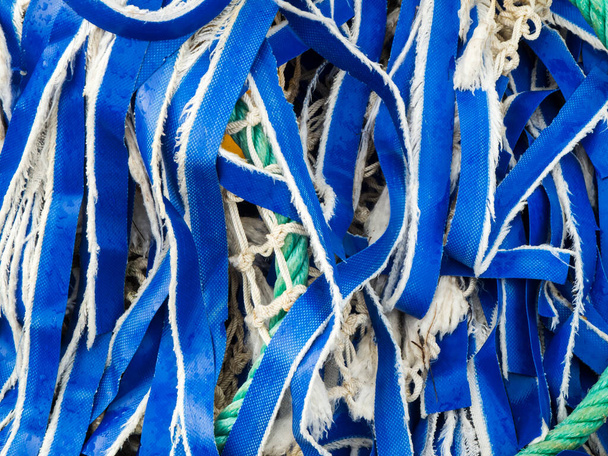 Vista de primer plano de marco completo de cintas textiles azules deshilachadas en una bola de redes de pesca. - Foto, Imagen