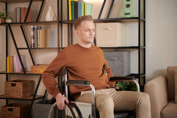 自宅で車椅子に座っている障害のある抑圧された若者 - 写真・画像