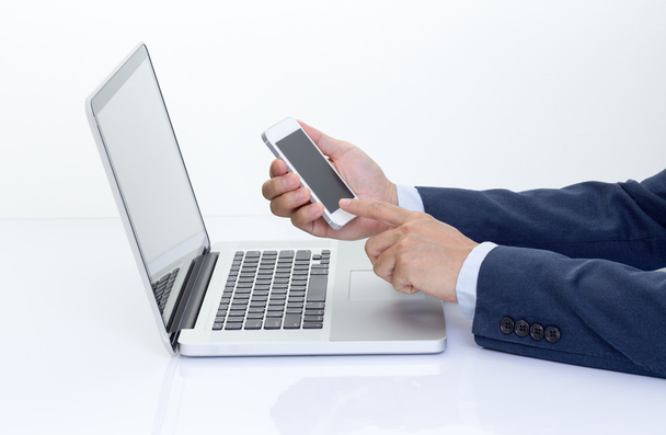 Businessman hand holding mobile phone with laptop computer - 写真・画像