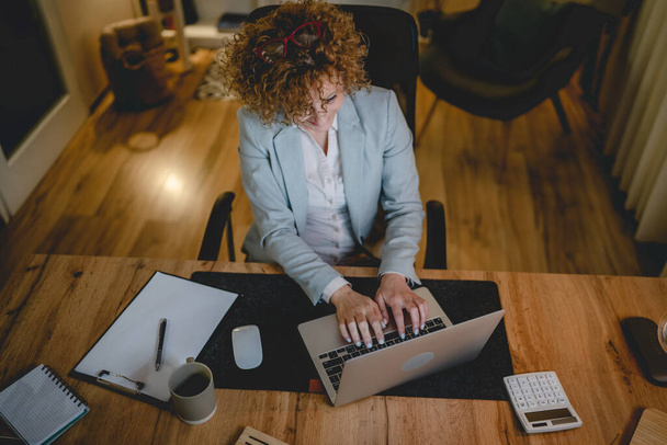 Eine Frau kaukasischen weiblichen Arbeit, während am Schreibtisch sitzen Laptop verwenden Unternehmerin oder Managerin Anwalt arbeiten in der Nacht zuversichtlich Vorbereitung Strategie und machen Plan echte Menschen kopieren Raum - Foto, Bild