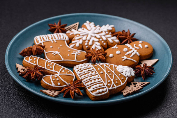 Krásné vánoční perníkové sušenky různých barev na keramické desce na tmavém betonovém stole - Fotografie, Obrázek