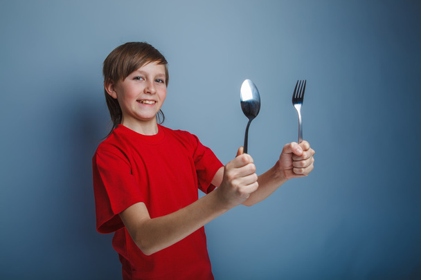 chico adolescente europeo apariencia en un rojo camisa sosteniendo un tenedor un
 - Foto, imagen