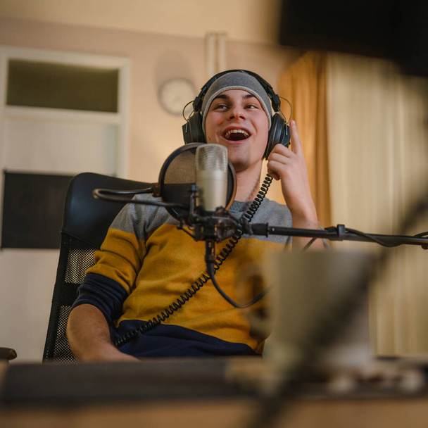 One man caucasian male blogger or vlogger gesticulating while streaming video podcast in broadcasting studio use microphone and headphones famous influencer shooting video for channel podcast - Foto, Imagen