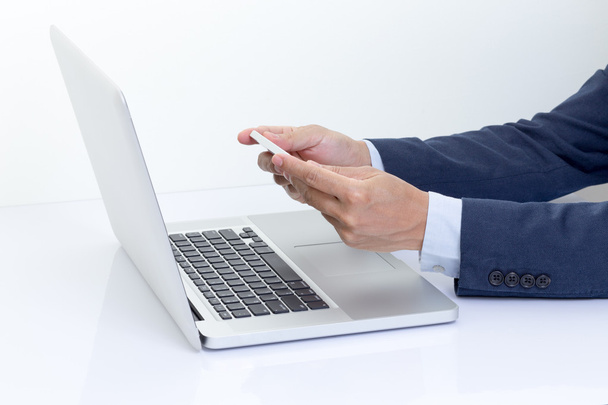 Businessman hands holding mobile phone with laptop computer - Foto, imagen
